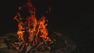 CLOSE UP: Large bright orange campfire burning inside a brick enclosed fire pit.