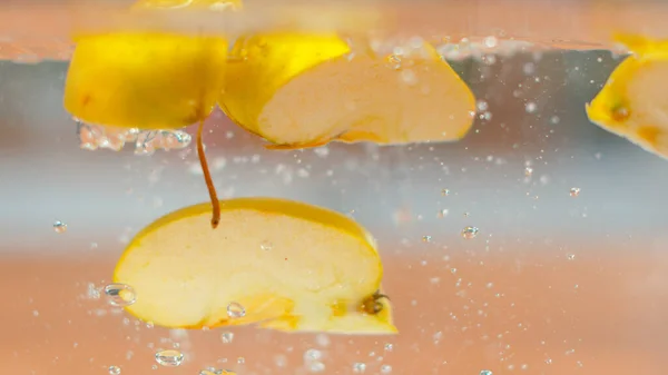 MACRO: Sliced golden delicious apple make a splash after falling into water. —  Fotos de Stock