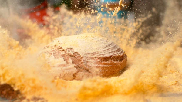 CHIUDI: Una pagnotta di pane marrone cade in una pila di farina di mais e la disperde. — Foto Stock