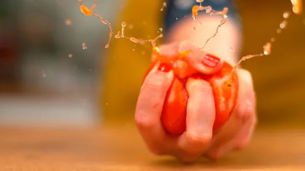 MACRO, DOF: Biologische tomaat explodeert in de hand van een vrouwelijke chef terwijl ze erin knijpt. — Stockfoto