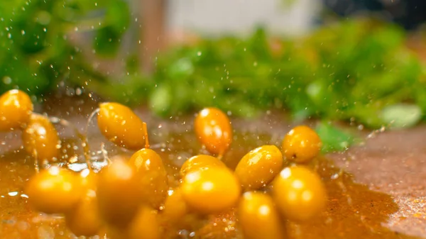 MACRO Las aceitunas maduras caen en un charco de aceite de oliva y lo salpican sobre la mesa . —  Fotos de Stock