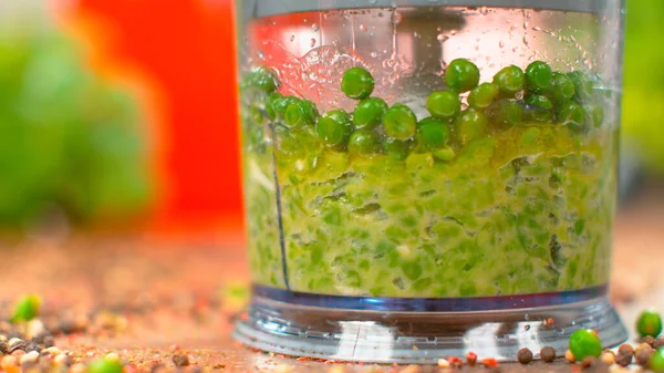 MACRO: Ervilhas verdes orgânicas cruas são misturadas em um molho frio em um processador de alimentos. — Fotografia de Stock