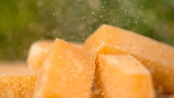 MACRO: Deliciosos flocos de parmesão caem sobre os cubos de queijo na tábua de madeira. — Fotografia de Stock