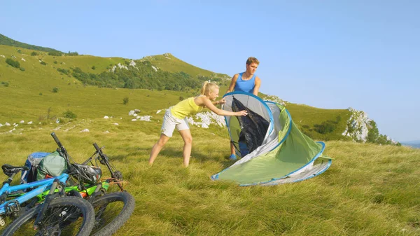 Active sporty couple mountain biking in the Alps setting up their pop up tent. — Stock Photo, Image