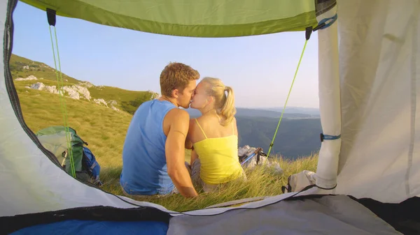 CHIUDI: Coppia di turisti spensierati innamorati che si baciano seduti davanti alla tenda. — Foto Stock