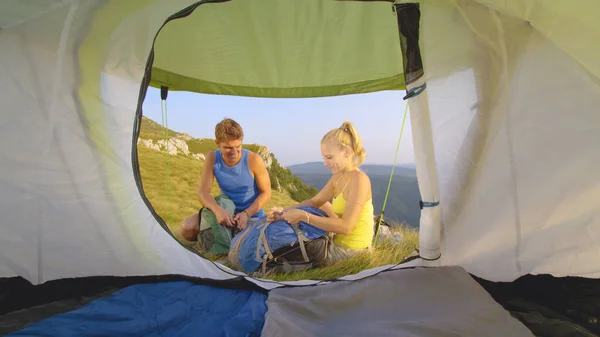 CLOSE UP Fröhliches Wandererpaar packt seine Rucksäcke, bevor es sein Zelt verlässt — Stockfoto