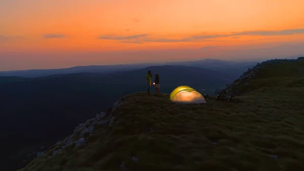 Man holds up a lantern while enjoying a romantic date in mountains with a girl. — стоковое фото