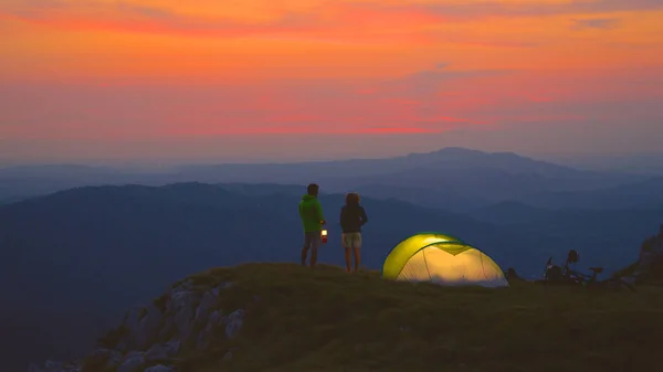 Unbekümmertes Paar plaudert an einem kalten Sommerabend in den Bergen am Zelt. — Stockfoto