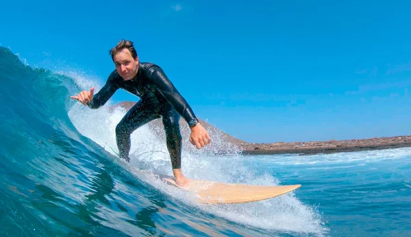 CLOSE UP: Glad manlig surfare rider en våg och ger kameran shaka tecken. — Stockfoto
