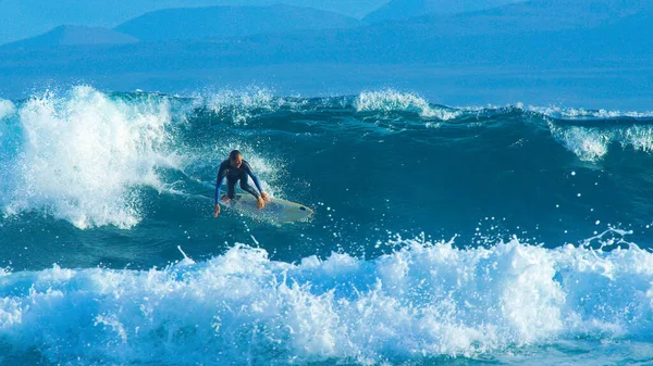 Grote vloedgolf duwt de jonge surfer naar de kust van de Canarische Eilanden. — Stockfoto