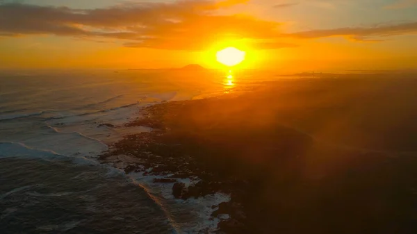 LENS FLARE: gyönyörű naplemente megvilágítja a nyugodt óceán és a zord partvonal — Stock Fotó