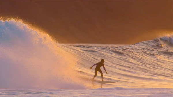 Gul kväll solsken lyser upp den natursköna och surfare ridning vågor — Stockfoto