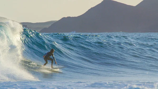 Experienced young male surfer carves over a large crashing wave on a sunny day. — Stock Photo, Image