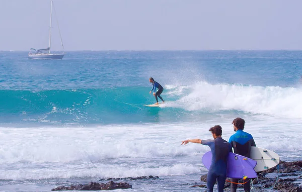 Δροσερό surfer μάγκα σκάλισμα ένα όμορφο κύμα μπλε βαρέλι ως φίλοι τον παρακολουθήσουν. — Φωτογραφία Αρχείου