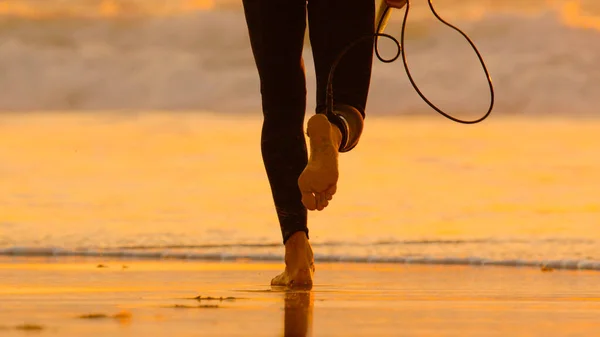 LOW ANGLE: Unrecognizable surfer in wetsuit running towards the foaming ocean. — Stock Photo, Image