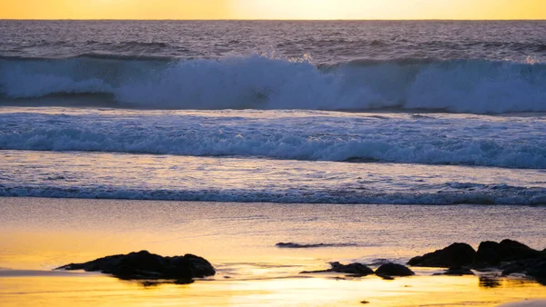 Small waves crash and wash the empty sandy shore of tropical island at sunset. — Stock Photo, Image