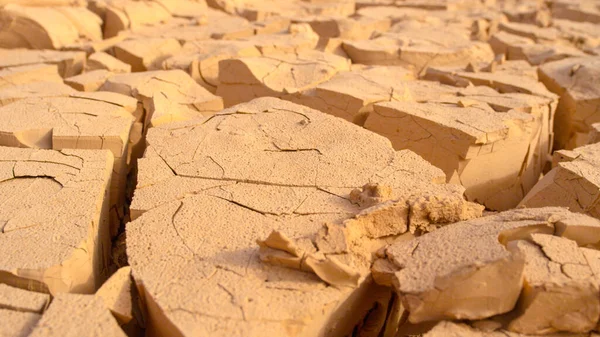 MACRO, DOF: Small particles of mud breaking off of larger pieces of dry soil.