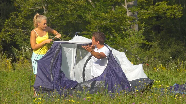 Irriteret kæreste skændes med kæreste, mens de opretter deres telt ved skov. - Stock-foto