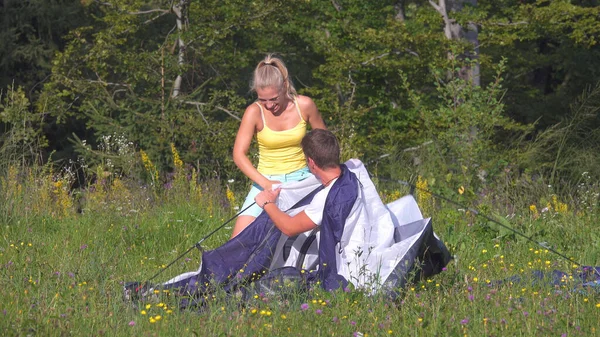 Unbekümmertes Paar hat Spaß beim Zeltaufbau während einer sommerlichen Zeltreise. — Stockfoto
