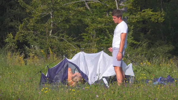 Junger Mann ärgert sich, als das Touristenpaar Probleme beim Zeltaufbau hat. — Stockfoto