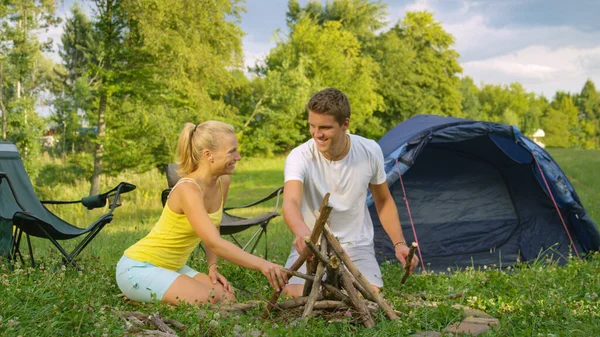 CLOSE UP: Lächelndes junges Paar baut gemeinsam ein Lagerfeuer am Zelt. — Stockfoto