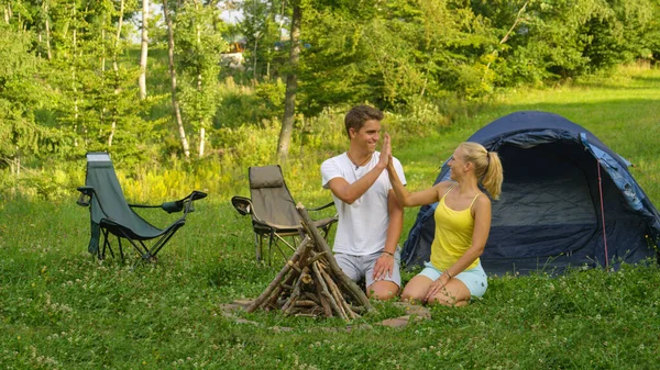 Joyful haired blonde girl high fives her boyfriend after collecting firewood. — стоковое фото