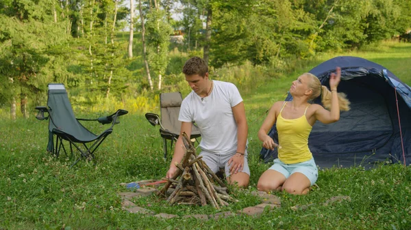 Schöne Mädchen wird von Wanzen umschwärmt, während ihr Freund ein Lagerfeuer zubereitet. — Stockfoto