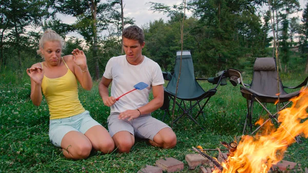 CLOSE UP: Young female camper gets scared of a big bug buzzing around campfire. — Stock Photo, Image