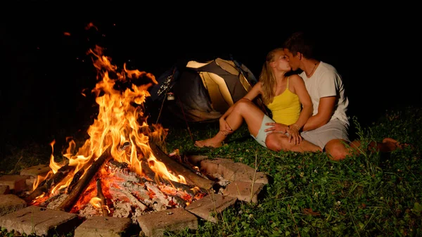 FECHAR UP: Casal despreocupado acampar no riso selvagem e beijo na fogueira. — Fotografia de Stock