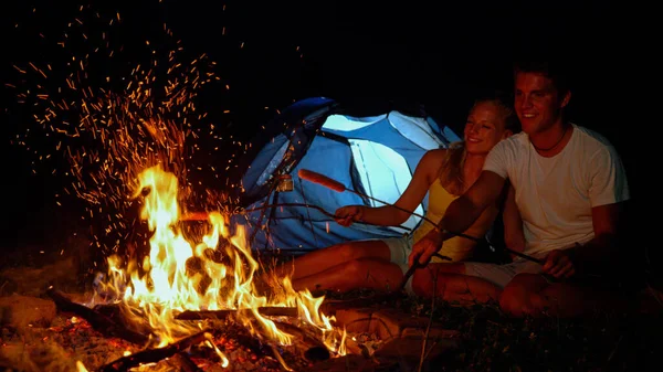 FECHAR-se: Camper feliz batendo fogo enquanto assar salsichas com a namorada. — Fotografia de Stock