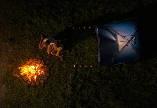 TOP DOWN: Joyful couple camping in the wild roasting sausages over the campfire. — Stock Photo, Image