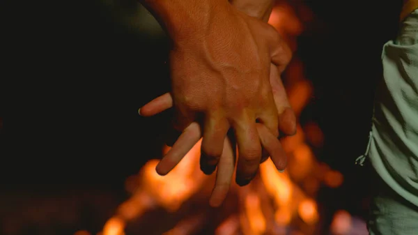 MACRO: nierozpoznany młody mężczyzna i kobieta trzymający się za ręce nad ogniskiem. — Zdjęcie stockowe