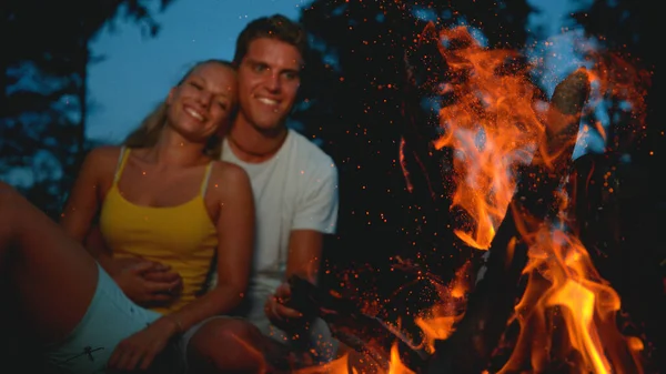 CLOSE UP, DOF: Young couple cuddling and looking at the big burning campfire. — Foto de Stock