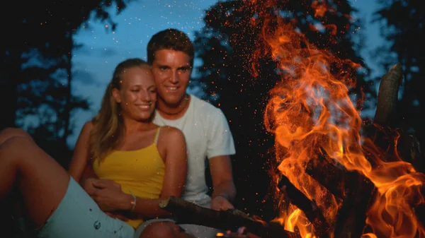 FECHAR UP: Smiling jovem casal goza de uma calma noite de verão perto da fogueira. — Fotografia de Stock