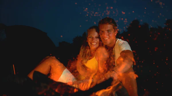 CLOSE UP: Happy couple sitting by the campfire on a romantic summer evening. — Foto de Stock