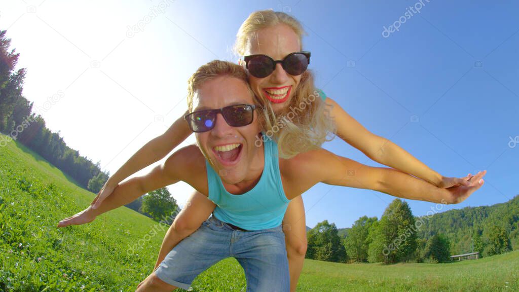 SUN FLARE: Excited man giving his girlfriend a piggyback ride on a sunny day.