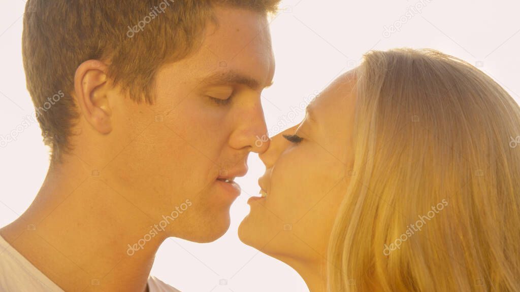 CLOSE UP: Happy young woman and her boyfriend rubbing their noses together.