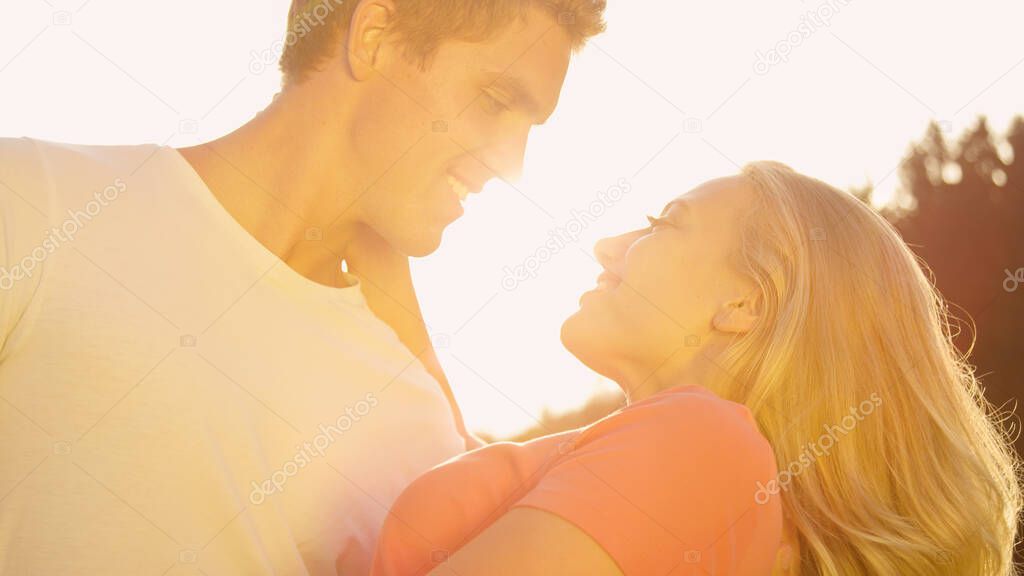 SUN FLARE: Strong Caucasian man holds the gorgeous woman as she leans back.