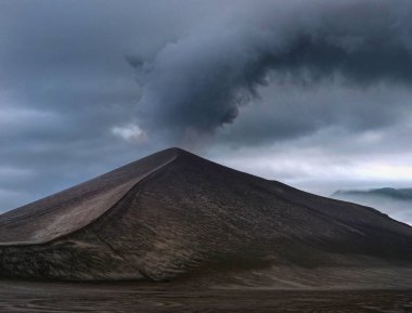 Thick grey clouds of smoke and ash rise from the active volcano in the Pacific.