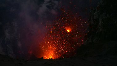 CLOSE UP: Glowing pieces of lava fly up in the air out of an active volcano.