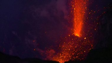 CLOSE UP: Bright red pieces of magma fly high up in the air after eruption.