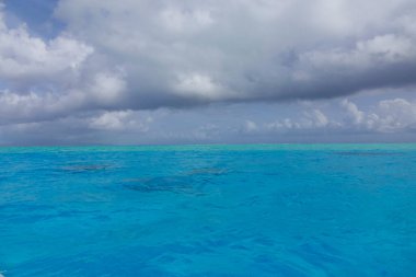 DRONE: Flying over the tranquil turquoise ocean on a cloudy summer afternoon.