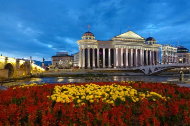 Majestic old town hall building overlooks the tranquil river flowing past garden