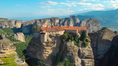 AERIAL: Stunning view of a rural town built on top of stunning towering boulder.