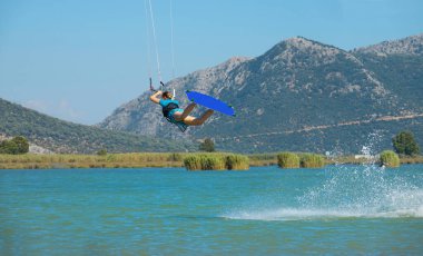 Extreme woman on summer vacation having fun doing tricks while kiteboarding.