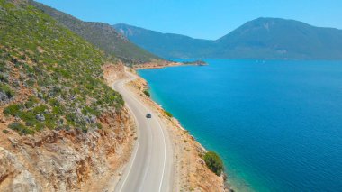 Bir sahil yolundan giderek adayı keşfe çıkan bir arabanın arkasında uçmak..