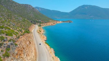 DRONE: Picturesque Mediterranean landscape surrounds car driving down the road.