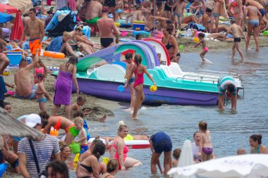 Children an adults enjoying their summer vacation on a crowded sandy beach.
