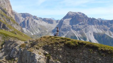 AERIAL: Unrecognizable female photographer taking photos of the rocky mountains.