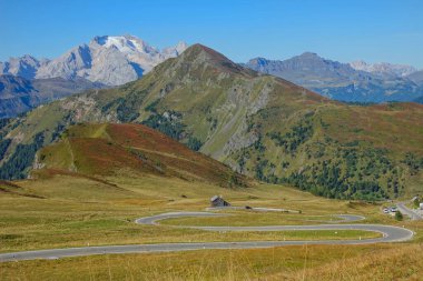 AERIAL: Flying over the pastures and towards a winding road in the mountains.